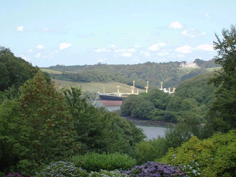 Ausblick von Trelissick Gardens: Ein in der Fal-M&uuml;ndung parkiertes Hochseeschiff. Im Hintergrund der Sitz der Lords Falmouth